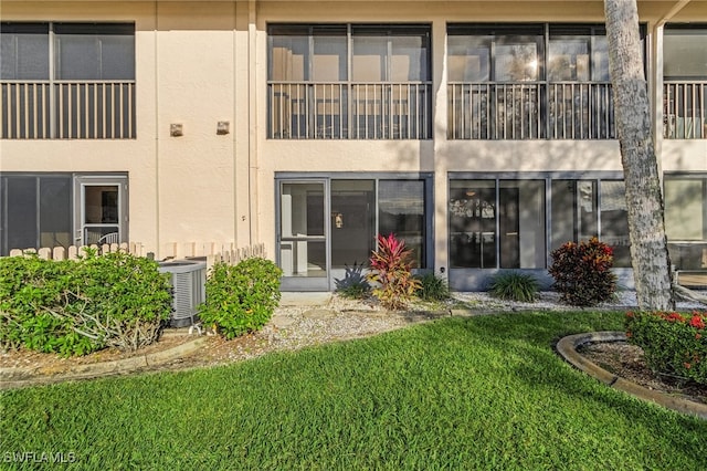 rear view of property with central AC and a yard