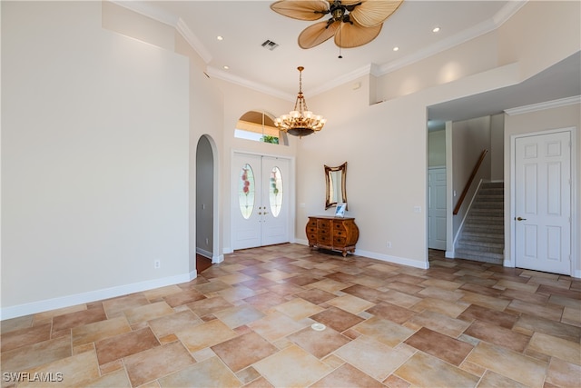 entryway with a high ceiling, ceiling fan with notable chandelier, french doors, and ornamental molding