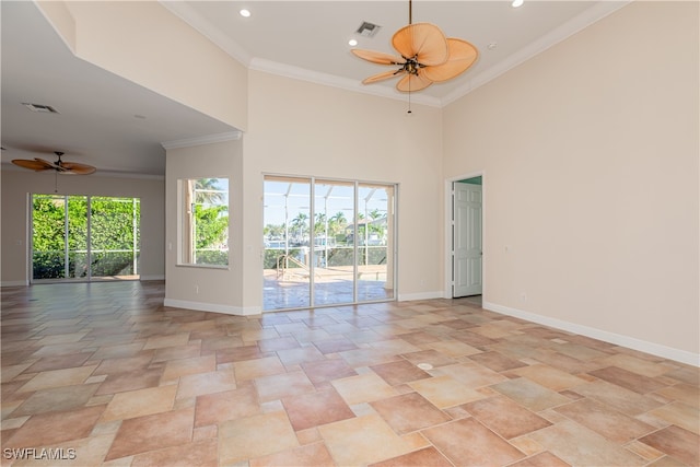 spare room with ceiling fan, a towering ceiling, and ornamental molding