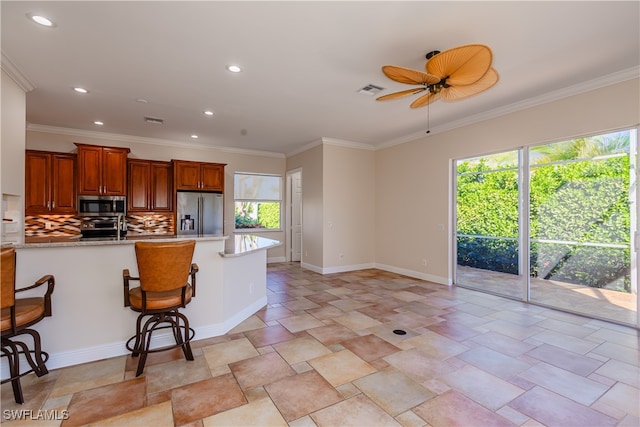 kitchen with tasteful backsplash, a breakfast bar, stainless steel appliances, and ornamental molding