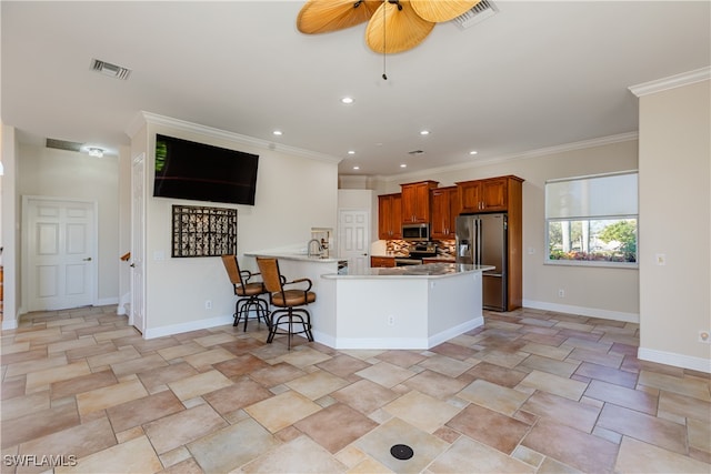 kitchen with kitchen peninsula, crown molding, decorative backsplash, a breakfast bar, and appliances with stainless steel finishes