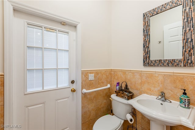 bathroom with toilet, tile walls, and sink