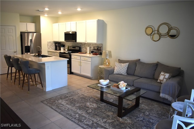 kitchen with an island with sink, appliances with stainless steel finishes, tasteful backsplash, and white cabinetry