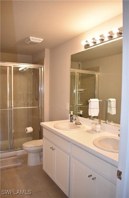 bathroom featuring tile patterned floors, a shower with shower door, vanity, and toilet