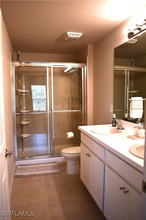 bathroom featuring tile patterned flooring, vanity, toilet, and an enclosed shower