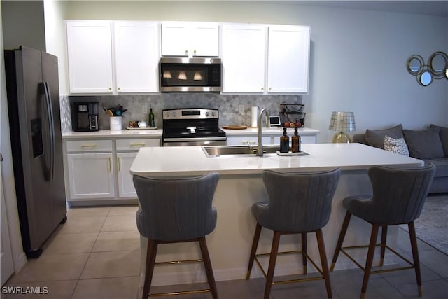 kitchen with white cabinetry, stainless steel appliances, light countertops, and a sink