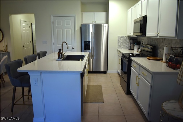 kitchen with a kitchen breakfast bar, a center island with sink, stainless steel appliances, and white cabinets