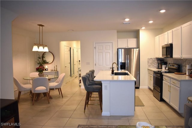 kitchen featuring tasteful backsplash, light tile patterned flooring, appliances with stainless steel finishes, and a sink