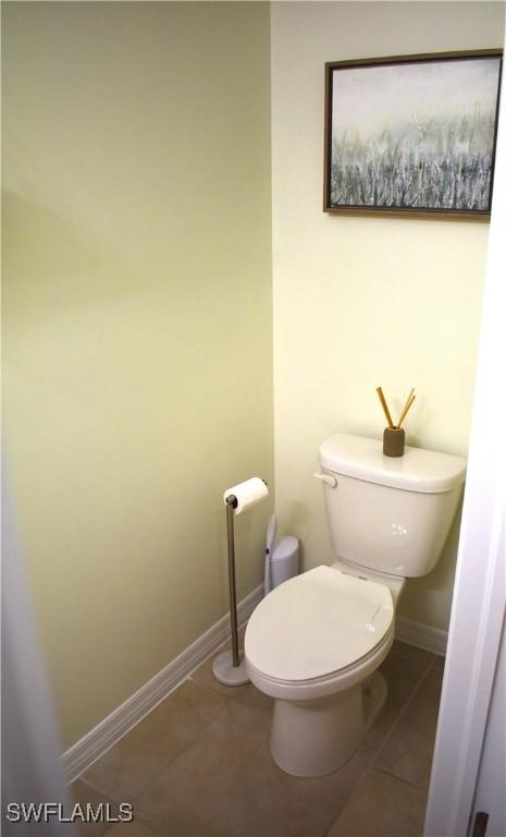 bathroom with baseboards, toilet, and tile patterned flooring