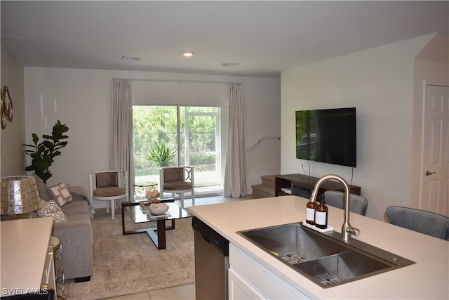 kitchen featuring stainless steel dishwasher, light tile patterned flooring, sink, and white cabinets