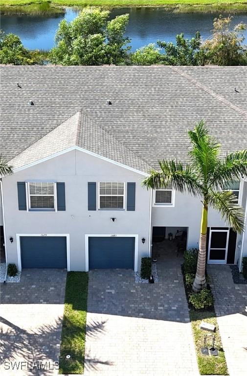 view of front of property featuring a shingled roof, a water view, and stucco siding