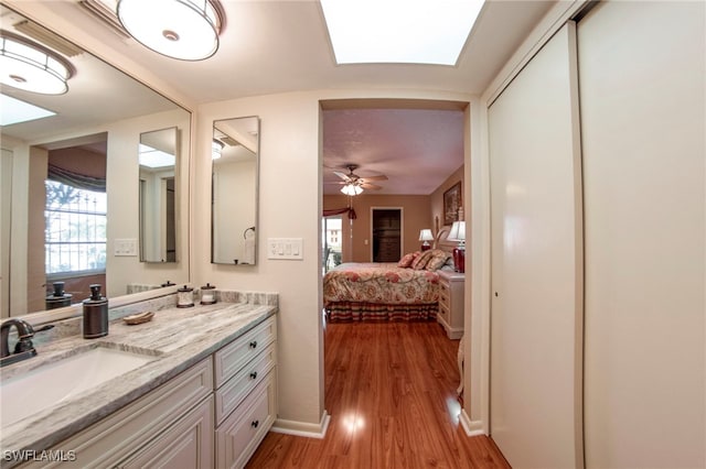 bathroom with vanity, hardwood / wood-style floors, ceiling fan, and a skylight