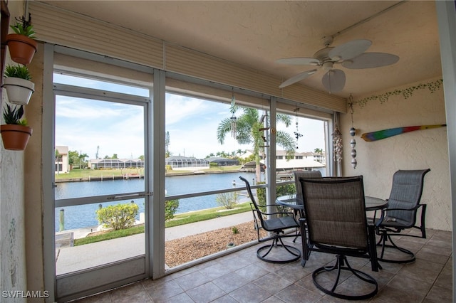 sunroom with a water view and ceiling fan