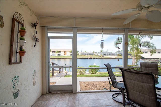 sunroom with ceiling fan and a water view