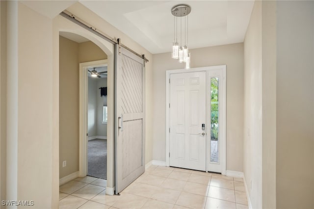 tiled foyer entrance with ceiling fan and a barn door