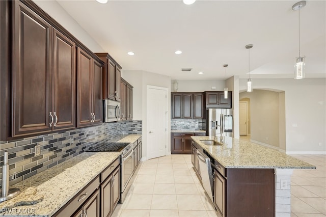 kitchen with an island with sink, stainless steel appliances, tasteful backsplash, sink, and pendant lighting