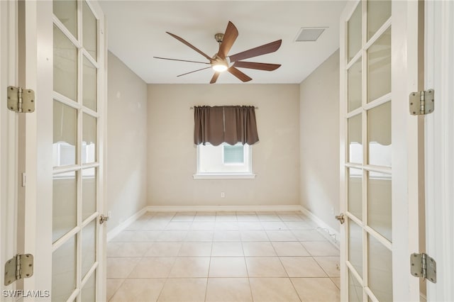 tiled spare room featuring french doors and ceiling fan