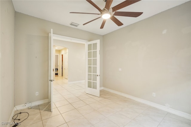 empty room with ceiling fan, light tile patterned floors, and french doors