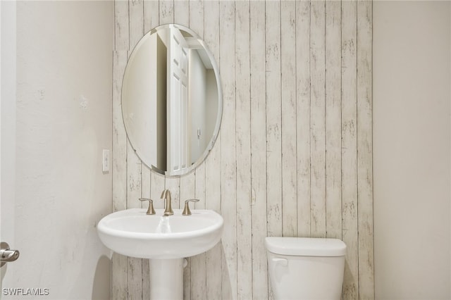 bathroom featuring wood walls and toilet