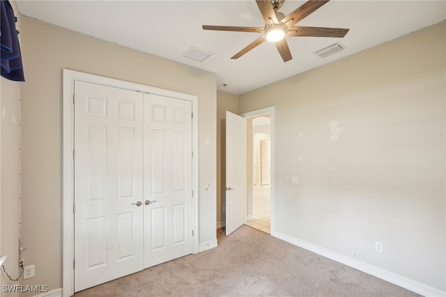 unfurnished bedroom featuring a closet, light colored carpet, and ceiling fan