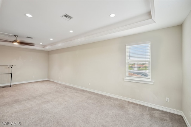 empty room featuring light carpet, a raised ceiling, and ceiling fan