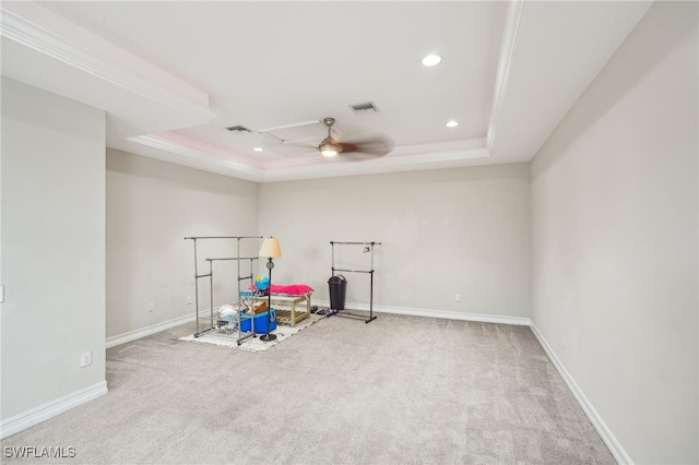 exercise room with a raised ceiling, carpet flooring, and ceiling fan