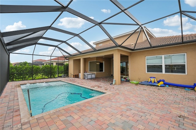 view of swimming pool featuring glass enclosure and a patio area