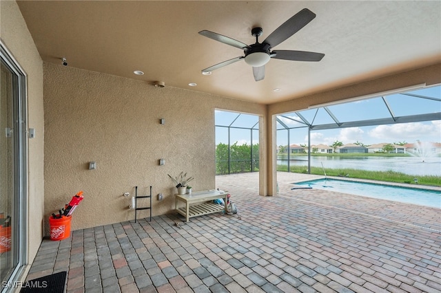 view of patio / terrace featuring a lanai, a water view, and ceiling fan