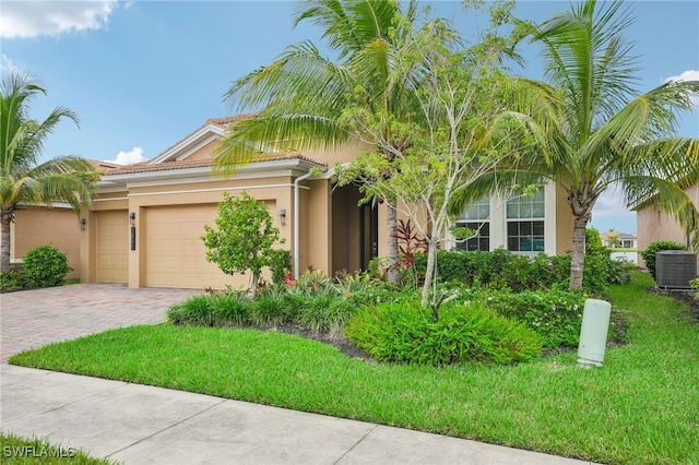 mediterranean / spanish home with a garage, a front lawn, and central air condition unit