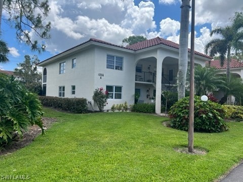 rear view of house featuring stucco siding, a tile roof, stairway, and a lawn