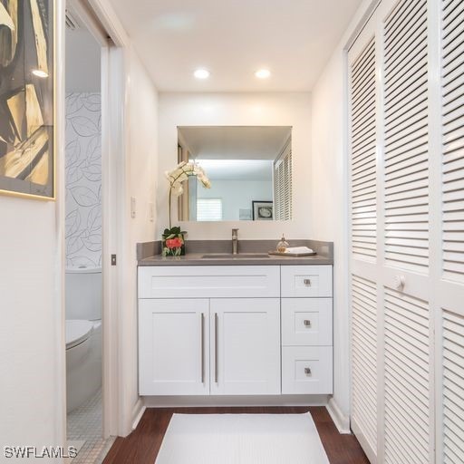bathroom featuring toilet, vanity, wood finished floors, and recessed lighting