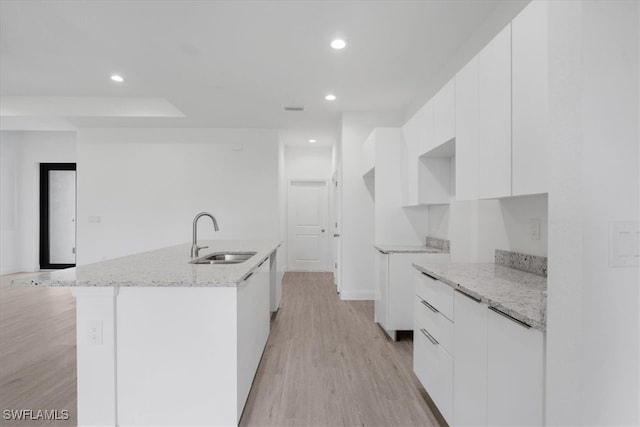 kitchen with an island with sink, white cabinets, and sink