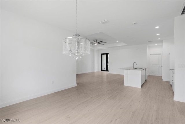 empty room with ceiling fan with notable chandelier, light hardwood / wood-style floors, and sink