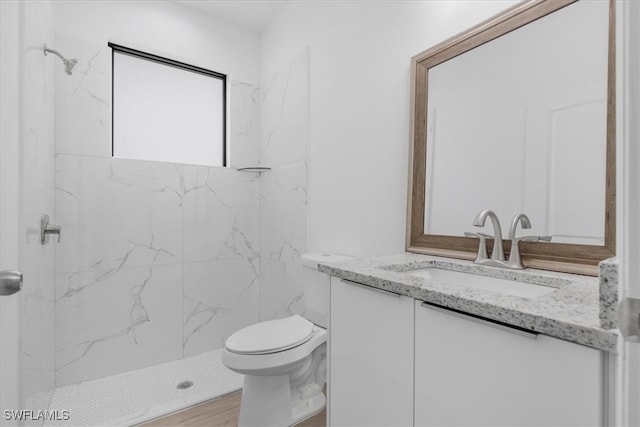 bathroom with vanity, hardwood / wood-style floors, toilet, and tiled shower