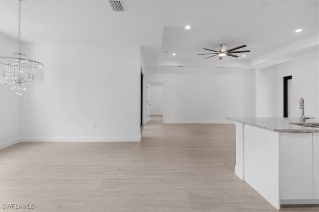 interior space featuring light hardwood / wood-style floors, ceiling fan, and a raised ceiling