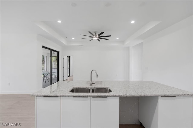 kitchen featuring ceiling fan, light stone countertops, sink, and white cabinetry