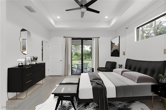 bedroom featuring ceiling fan, light hardwood / wood-style flooring, a tray ceiling, and access to outside