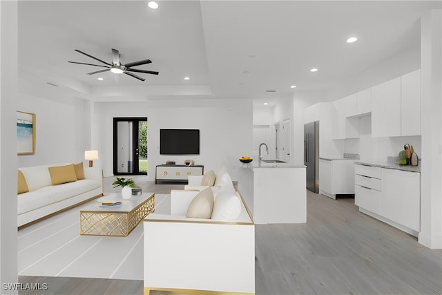 living room with light hardwood / wood-style flooring, ceiling fan, and sink