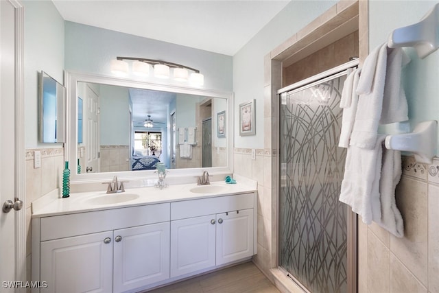 bathroom with tile walls, an enclosed shower, tile patterned floors, ceiling fan, and vanity