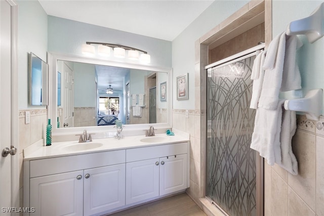 ensuite bathroom with a sink, tile walls, connected bathroom, and a stall shower