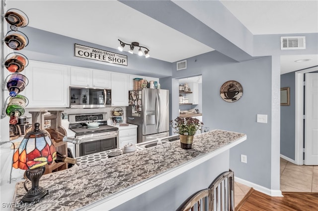 kitchen featuring appliances with stainless steel finishes, kitchen peninsula, white cabinetry, and light hardwood / wood-style floors