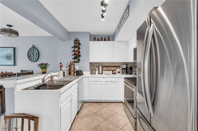 kitchen featuring kitchen peninsula, appliances with stainless steel finishes, a breakfast bar, and white cabinetry