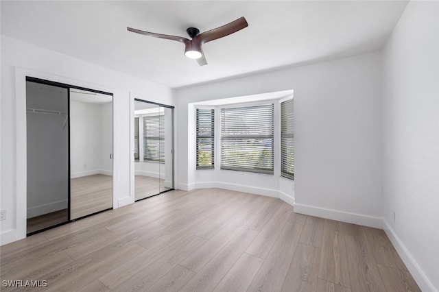 unfurnished bedroom with ceiling fan, two closets, and light wood-type flooring