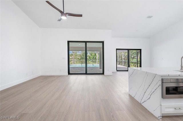 unfurnished living room with ceiling fan, sink, and light hardwood / wood-style flooring