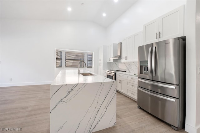 kitchen featuring white cabinets, sink, an island with sink, light stone counters, and stainless steel appliances