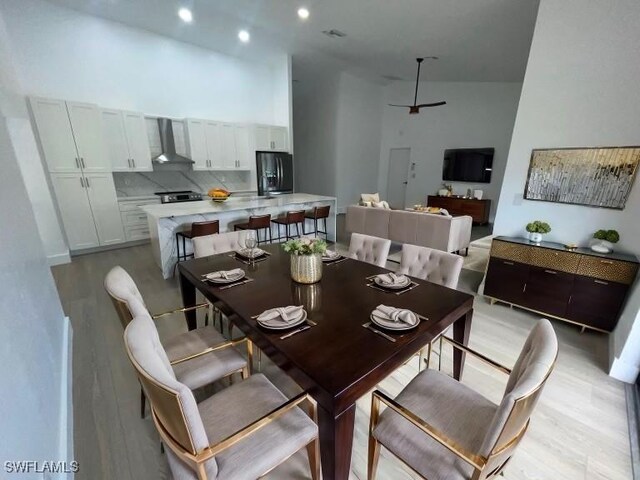 dining room with light wood-type flooring and high vaulted ceiling