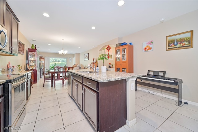 kitchen featuring hanging light fixtures, an island with sink, stainless steel appliances, sink, and a chandelier