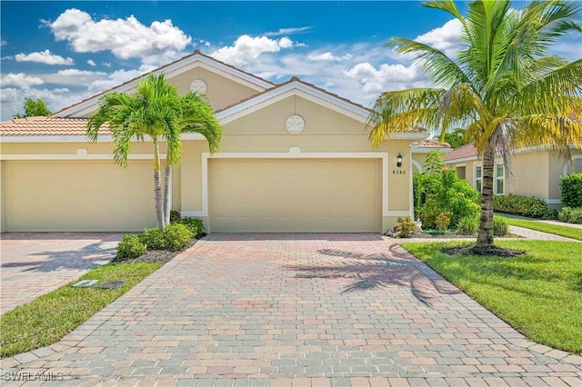 view of front of home featuring a garage, decorative driveway, a tile roof, and stucco siding