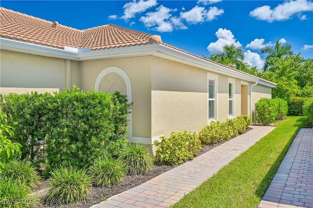 view of side of property with a tiled roof and stucco siding