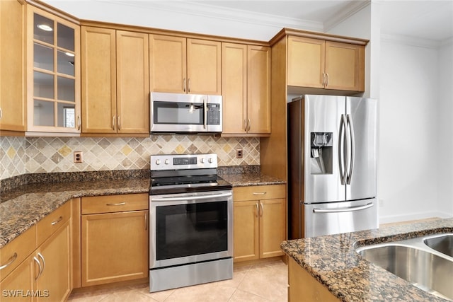 kitchen with appliances with stainless steel finishes, dark stone countertops, and light tile patterned flooring